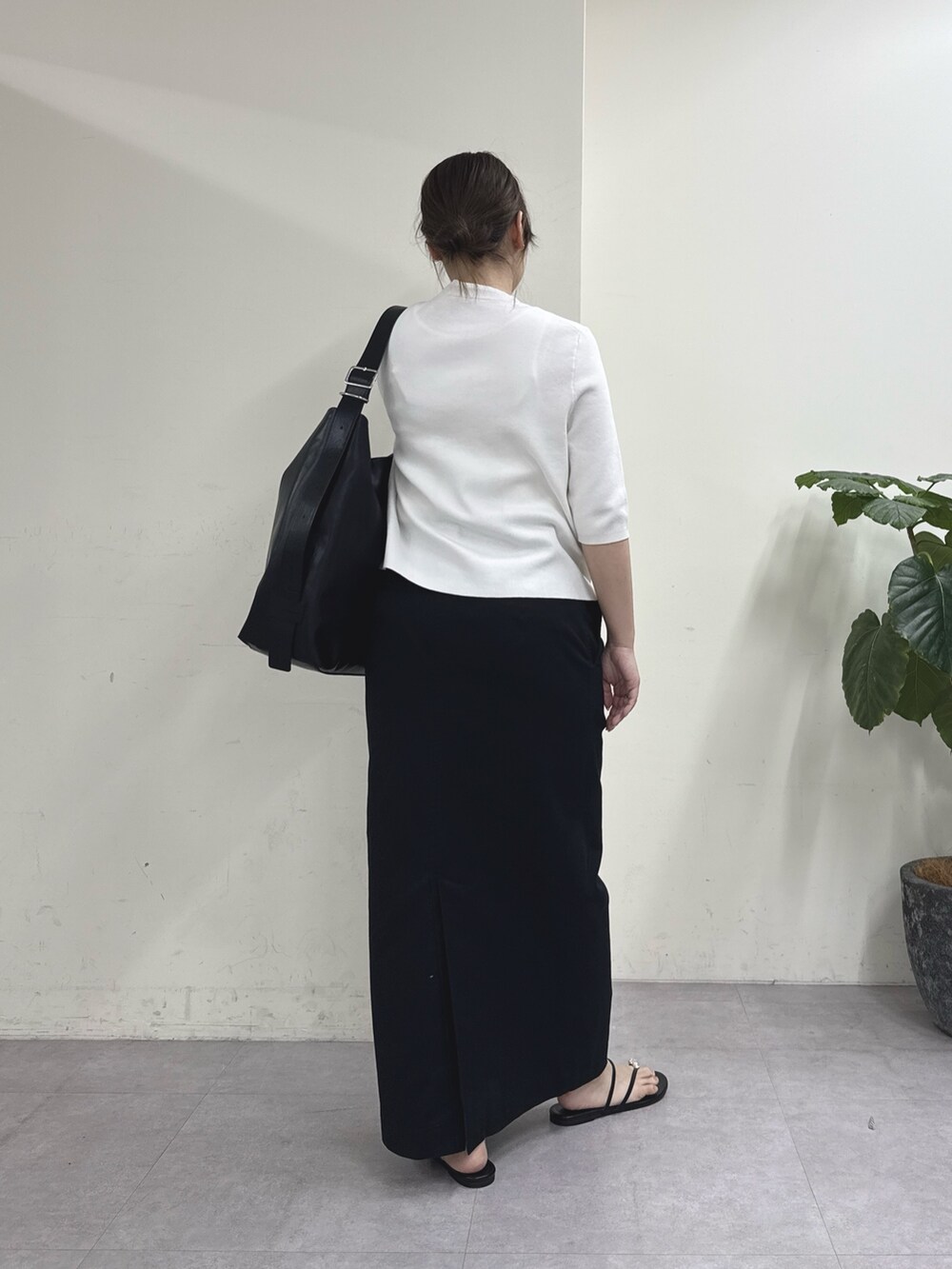 ブラック系のスカート、ホワイト系のカーディガン/ボレロ、ブラック系のショルダーバッグを着用したレディースの春コーディネートの3枚目の写真