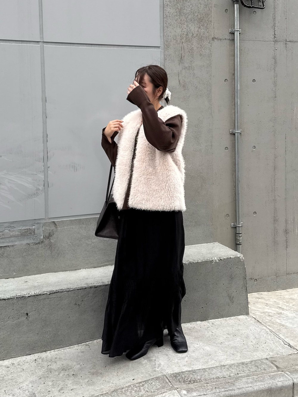 ブラック系のスカート、ブラック系のブーツ、ブラウン系のニット/セーターを着用したレディースの秋コーディネートの4枚目の写真