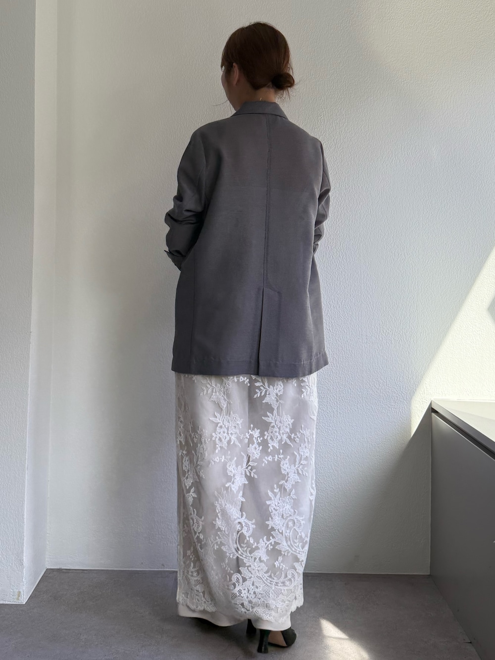 ホワイト系のワンピース、グレー系のテーラードジャケット、ブラック系のトートバッグを着用したレディースの冬コーディネートの3枚目の写真