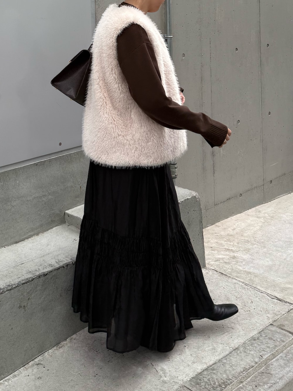 ブラック系のスカート、ブラック系のブーツ、ブラウン系のニット/セーターを着用したレディースの秋コーディネートの3枚目の写真