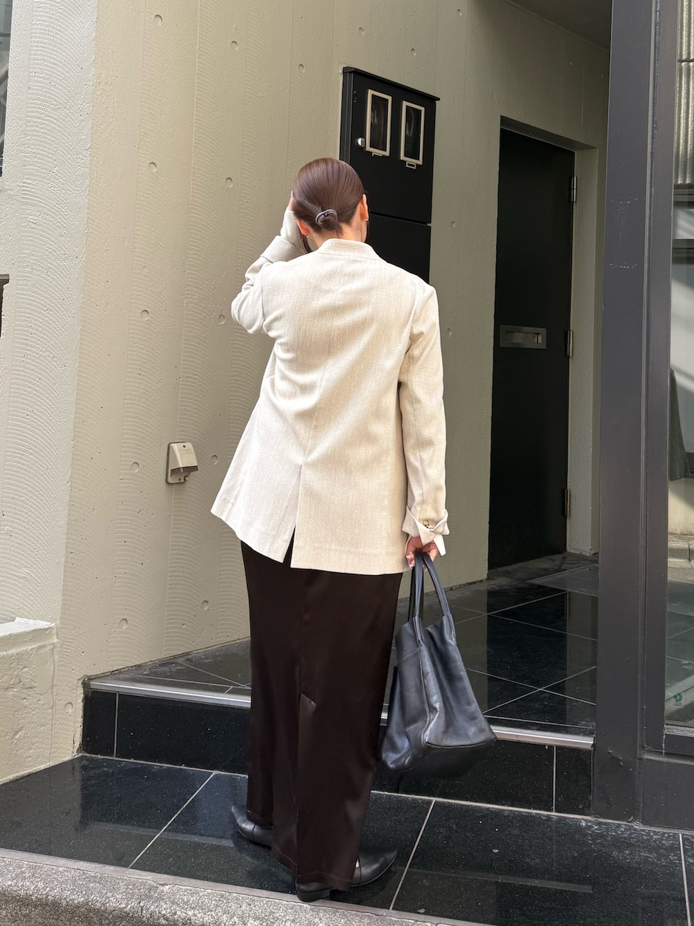 ブラウン系のスカート、ホワイト系のニット/セーター、ブラック系のトートバッグを着用したレディースの冬コーディネートの3枚目の写真