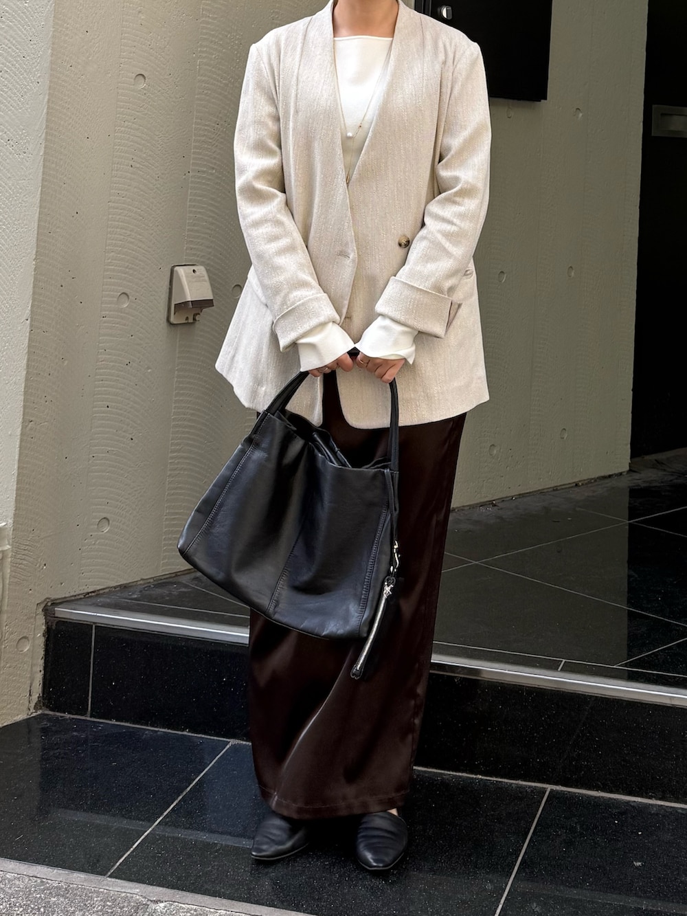 ブラウン系のスカート、ホワイト系のニット/セーター、ブラック系のトートバッグを着用したレディースの冬コーディネートの4枚目の写真