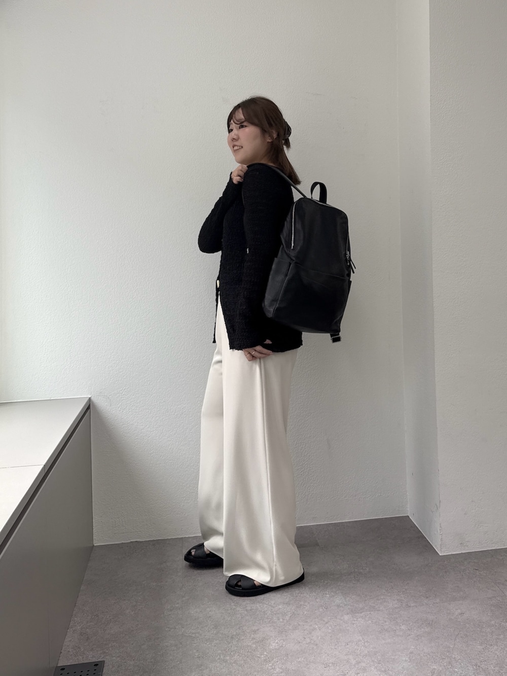 ブラック系のTシャツ/カットソー、ベージュ系のその他パンツ、ブラック系のサンダルを着用したレディースの春コーディネートの2枚目の写真