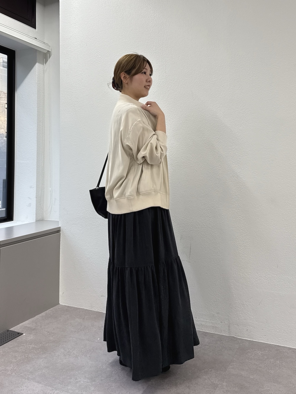 グレー系のワンピース、ブラック系のサンダル、ベージュ系のブルゾンを着用したレディースの春コーディネートの3枚目の写真