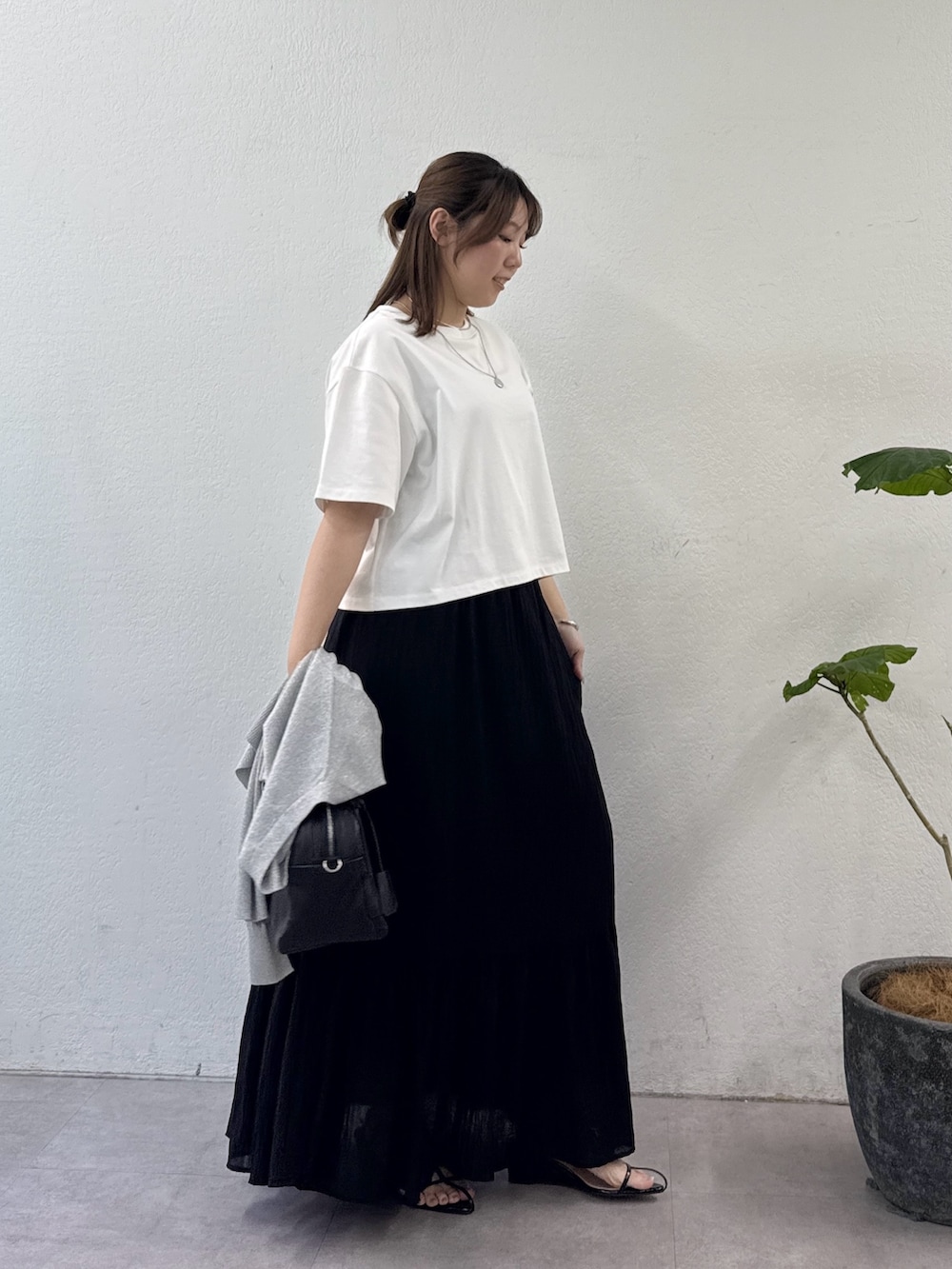 ブラック系のスカート、ブラック系のサンダル、ブラック系のボストンバッグを着用したレディースの夏コーディネートの2枚目の写真