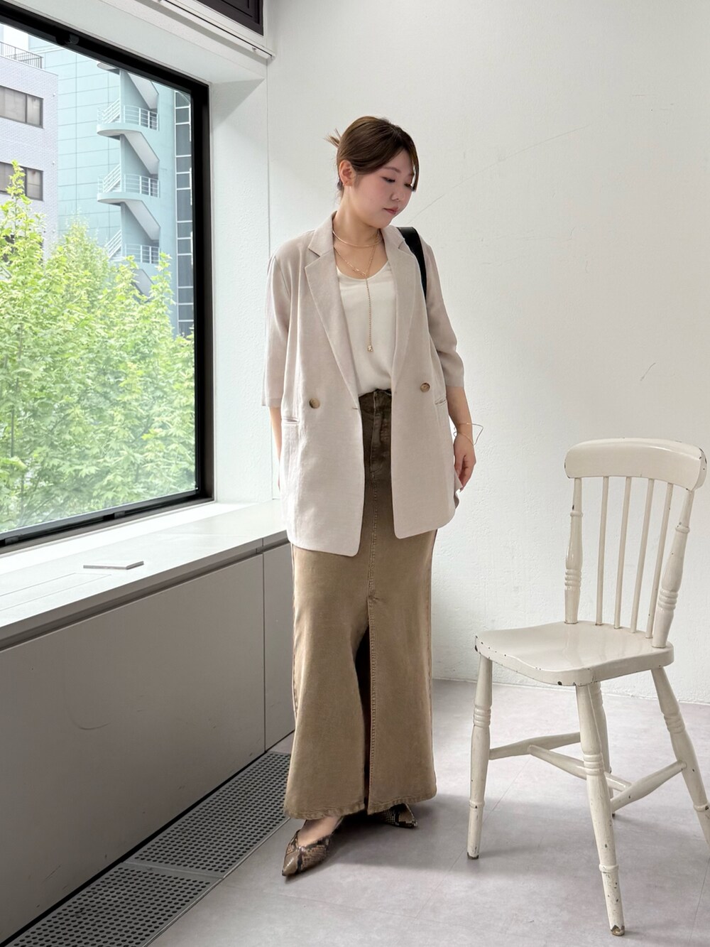 ブラウン系のパンプス、グリーン系のスカート、ホワイト系のキャミソールを着用したレディースの春コーディネートの4枚目の写真