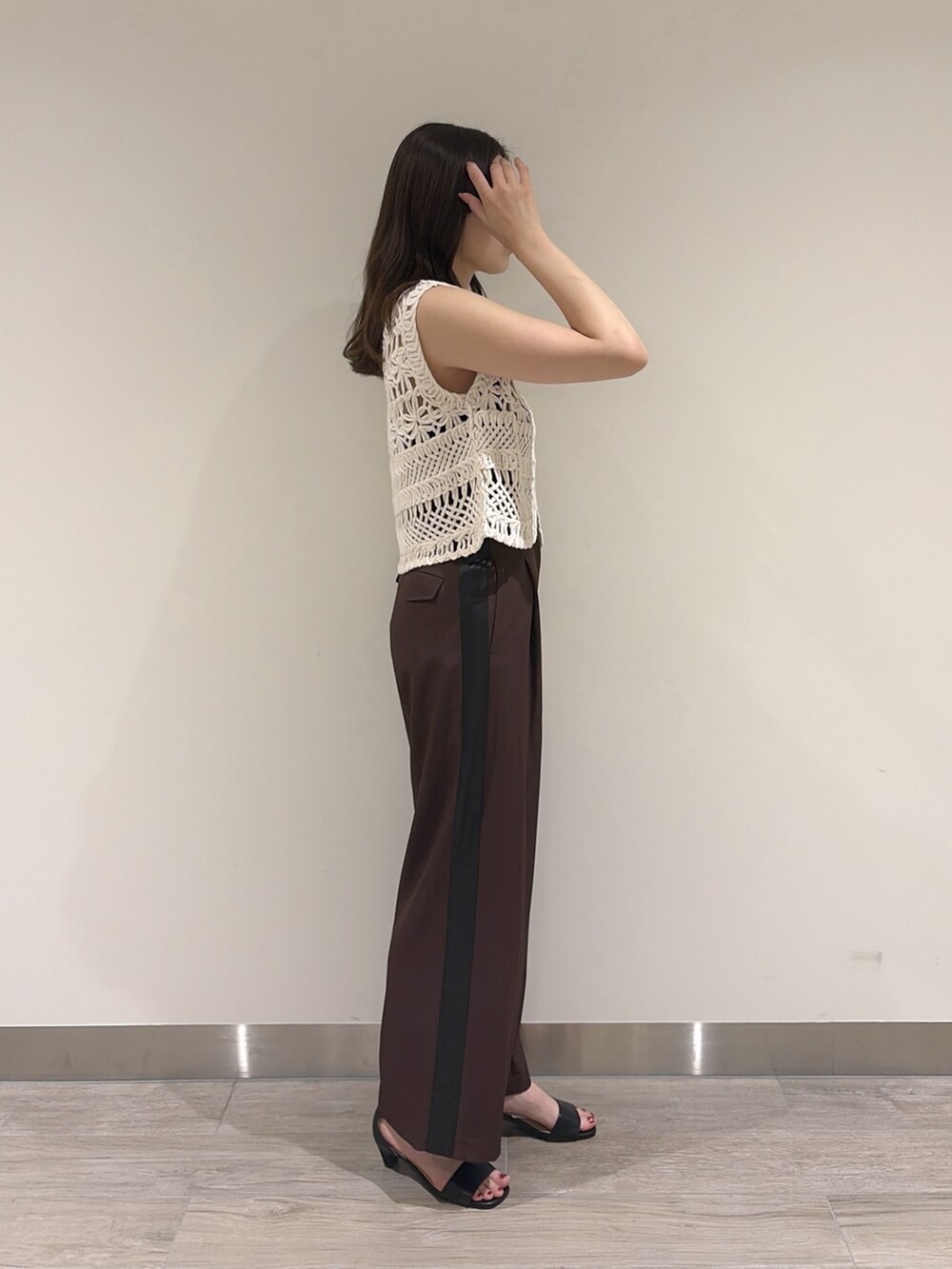 ホワイト系のベスト、ブラウン系のその他パンツ、ブラック系のサンダルを着用したレディースの夏コーディネートの5枚目の写真