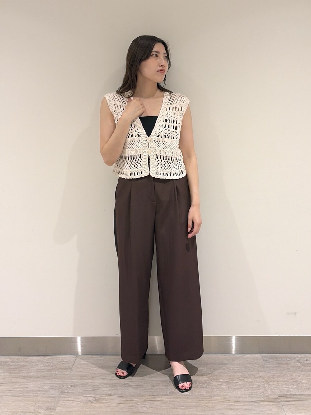 ホワイト系のベスト、ブラウン系のその他パンツ、ブラック系のサンダルを着用したレディースの夏コーディネートの3枚目の写真