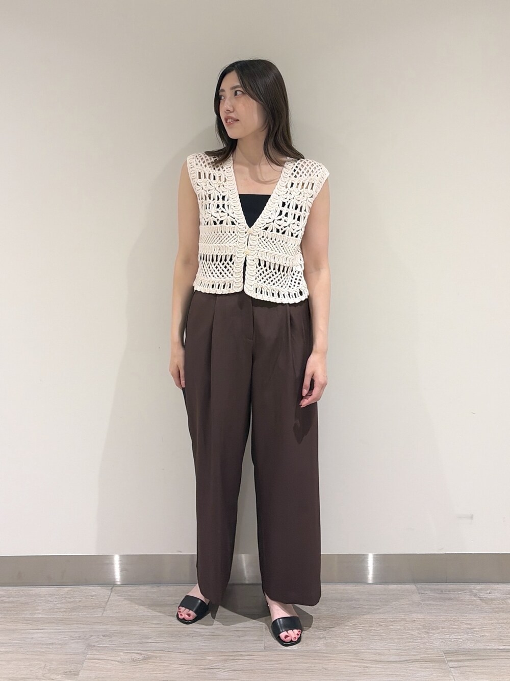 ホワイト系のベスト、ブラウン系のその他パンツ、ブラック系のサンダルを着用したレディースの夏コーディネートの4枚目の写真