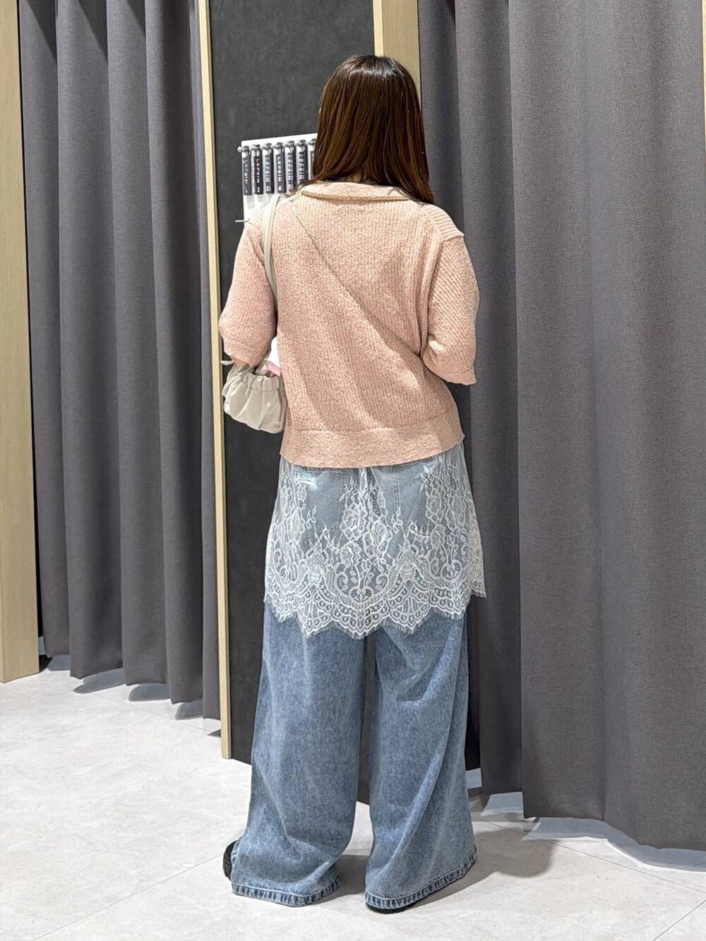 ブルー系のデニムパンツ、ホワイト系のボストンバッグ、ホワイト系のキャミソールを着用したレディースの春コーディネートの5枚目の写真