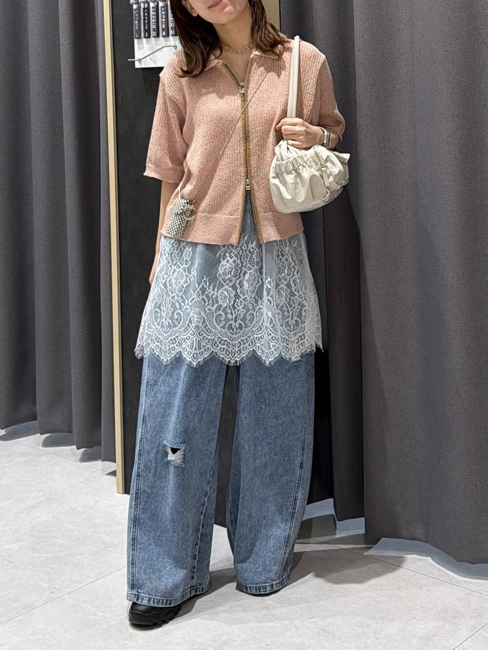 ブルー系のデニムパンツ、ホワイト系のボストンバッグ、ホワイト系のキャミソールを着用したレディースの春コーディネートの3枚目の写真