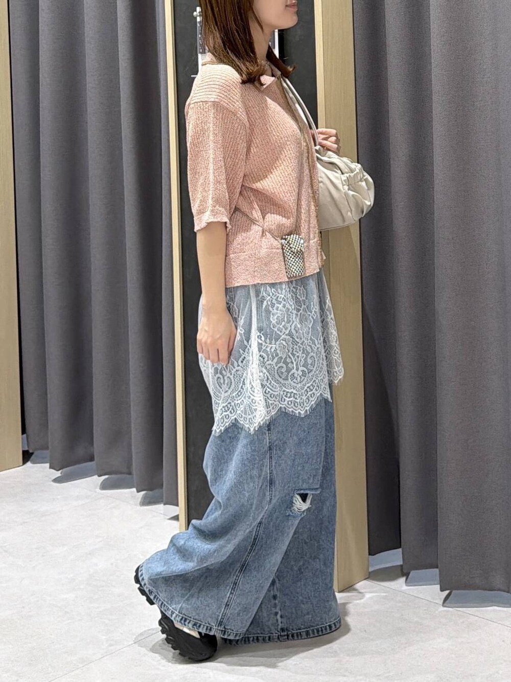 ブルー系のデニムパンツ、ホワイト系のボストンバッグ、ホワイト系のキャミソールを着用したレディースの春コーディネートの4枚目の写真