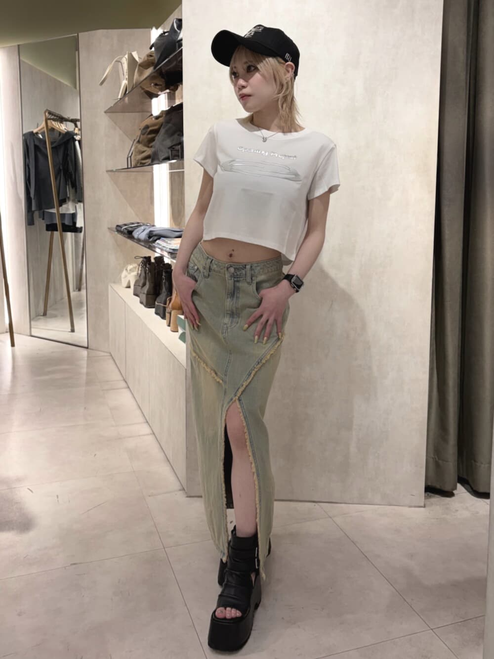 ブラック系のブーツ、ブルー系のデニムスカート、ホワイト系のTシャツ/カットソーを着用したレディースの春コーディネートの2枚目の写真