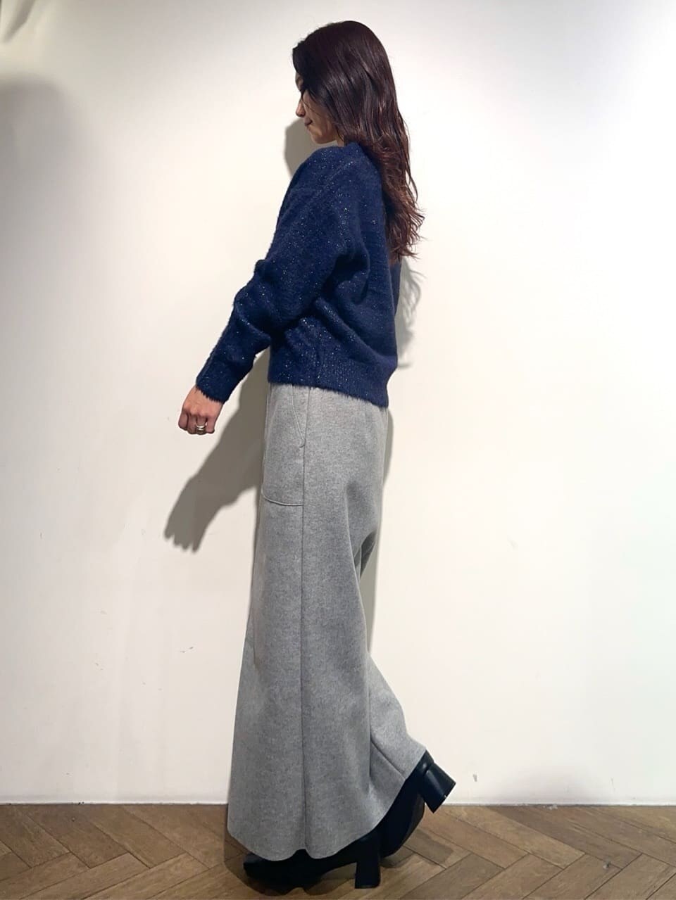 ブルー系のニット/セーター、グレー系のスカート、ホワイト系のトートバッグを着用したレディースの冬コーディネートの3枚目の写真