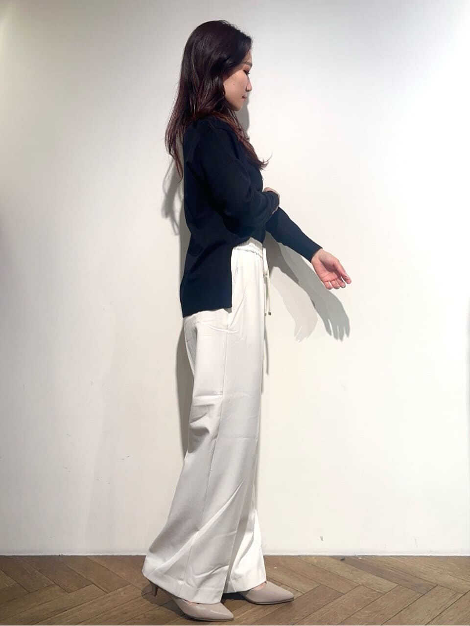 グレー系のノーカラーコート、ブラック系のニット/セーター、ホワイト系のその他パンツを着用したレディースの秋コーディネートの8枚目の写真