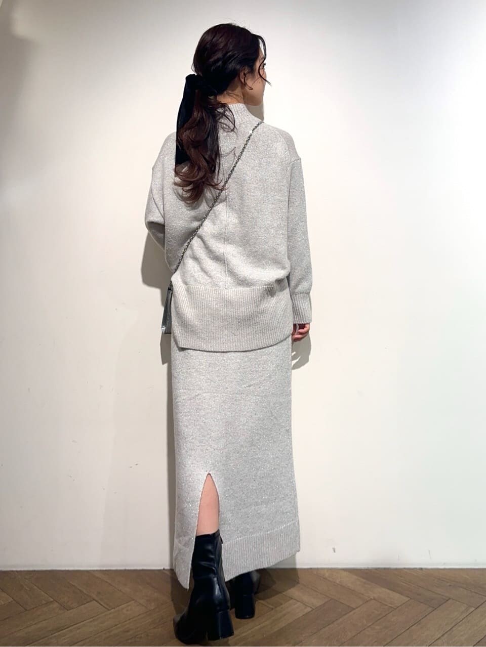 グレー系のニット/セーター、グレー系のスカート、シルバー系のショルダーバッグを着用したレディースの冬コーディネートの4枚目の写真
