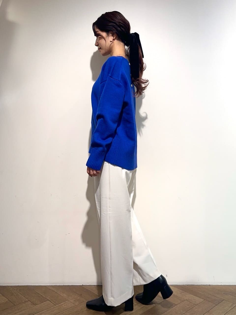 ブルー系のニット/セーター、ホワイト系のその他パンツ、ブラック系のブーツを着用したレディースの冬コーディネートの2枚目の写真