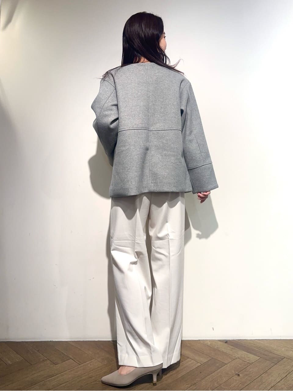 グレー系のノーカラーコート、ブラック系のニット/セーター、ホワイト系のその他パンツを着用したレディースの秋コーディネートの3枚目の写真
