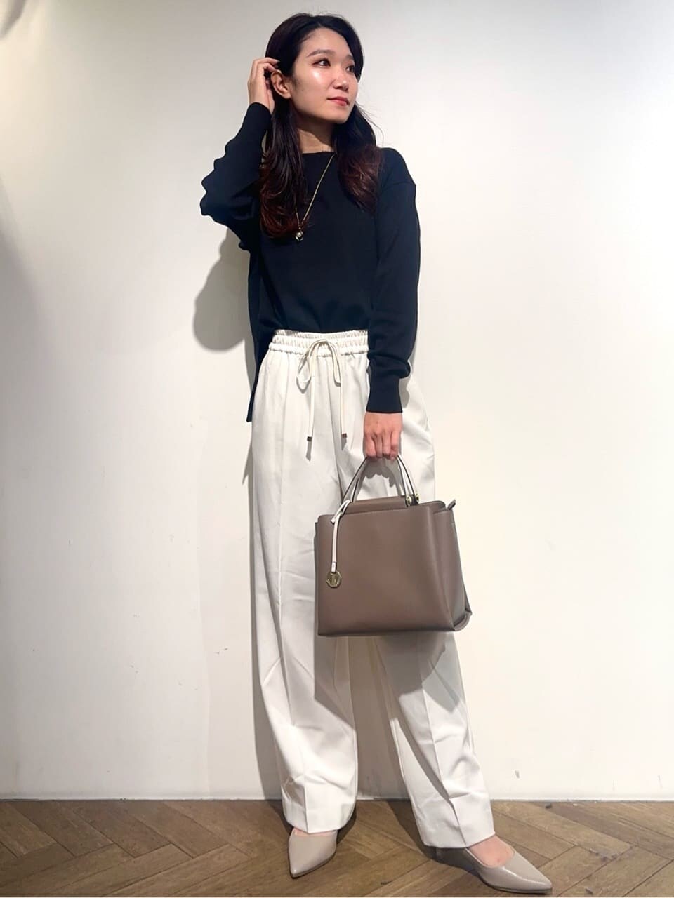 イエロー系のノーカラージャケット、ブラック系のニット/セーター、ホワイト系のその他パンツを着用したレディースの秋コーディネートの6枚目の写真