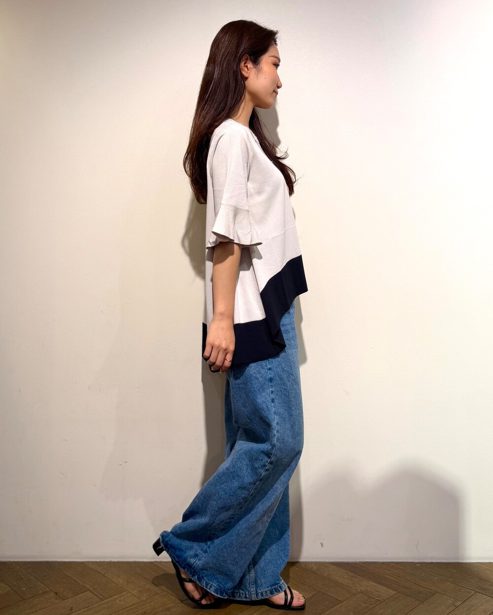 ベージュ系のニット/セーター、ブルー系のデニムパンツ、ブラウン系のハンドバッグを着用したレディースの春コーディネートの6枚目の写真