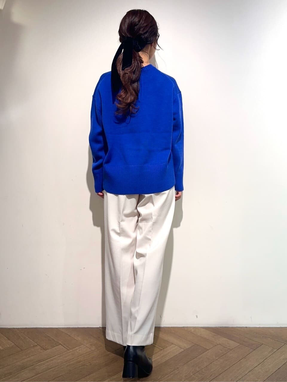 ブルー系のニット/セーター、ホワイト系のその他パンツ、ブラック系のブーツを着用したレディースの冬コーディネートの3枚目の写真