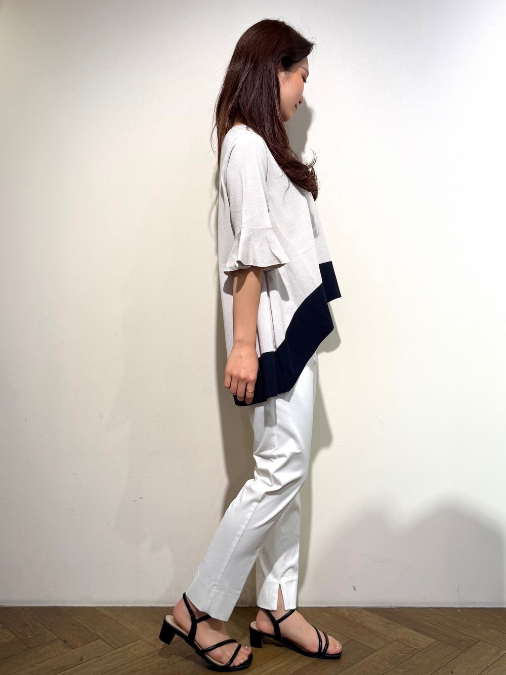 ベージュ系のニット/セーター、ホワイト系のその他パンツ、ブラック系のトートバッグを着用したレディースの春コーディネートの6枚目の写真