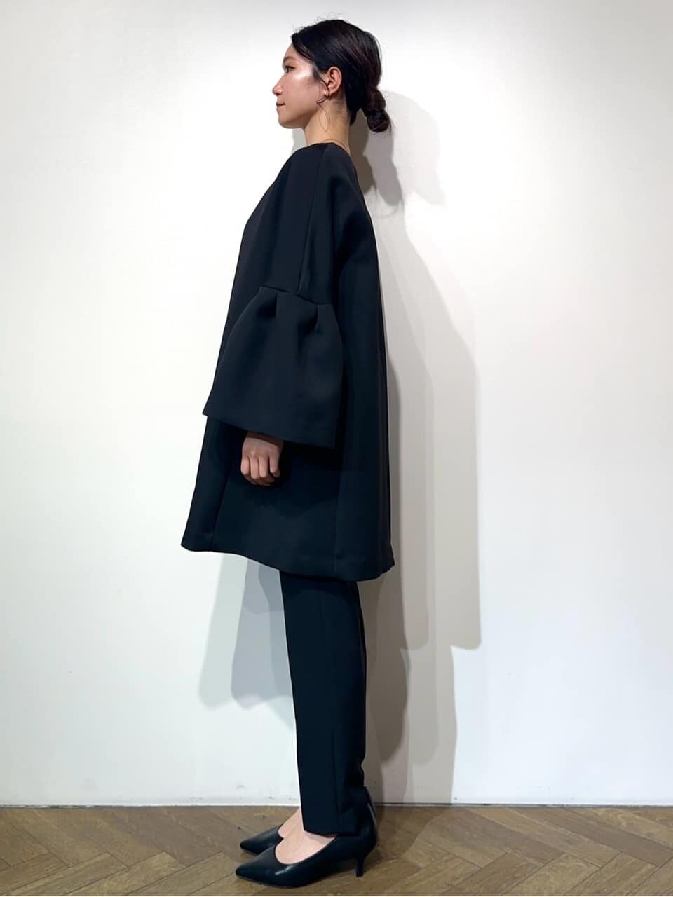 ブルー系のノーカラーコート、ホワイト系のシャツ/ブラウス、ブラック系のその他パンツを着用したレディースの冬コーディネートの2枚目の写真
