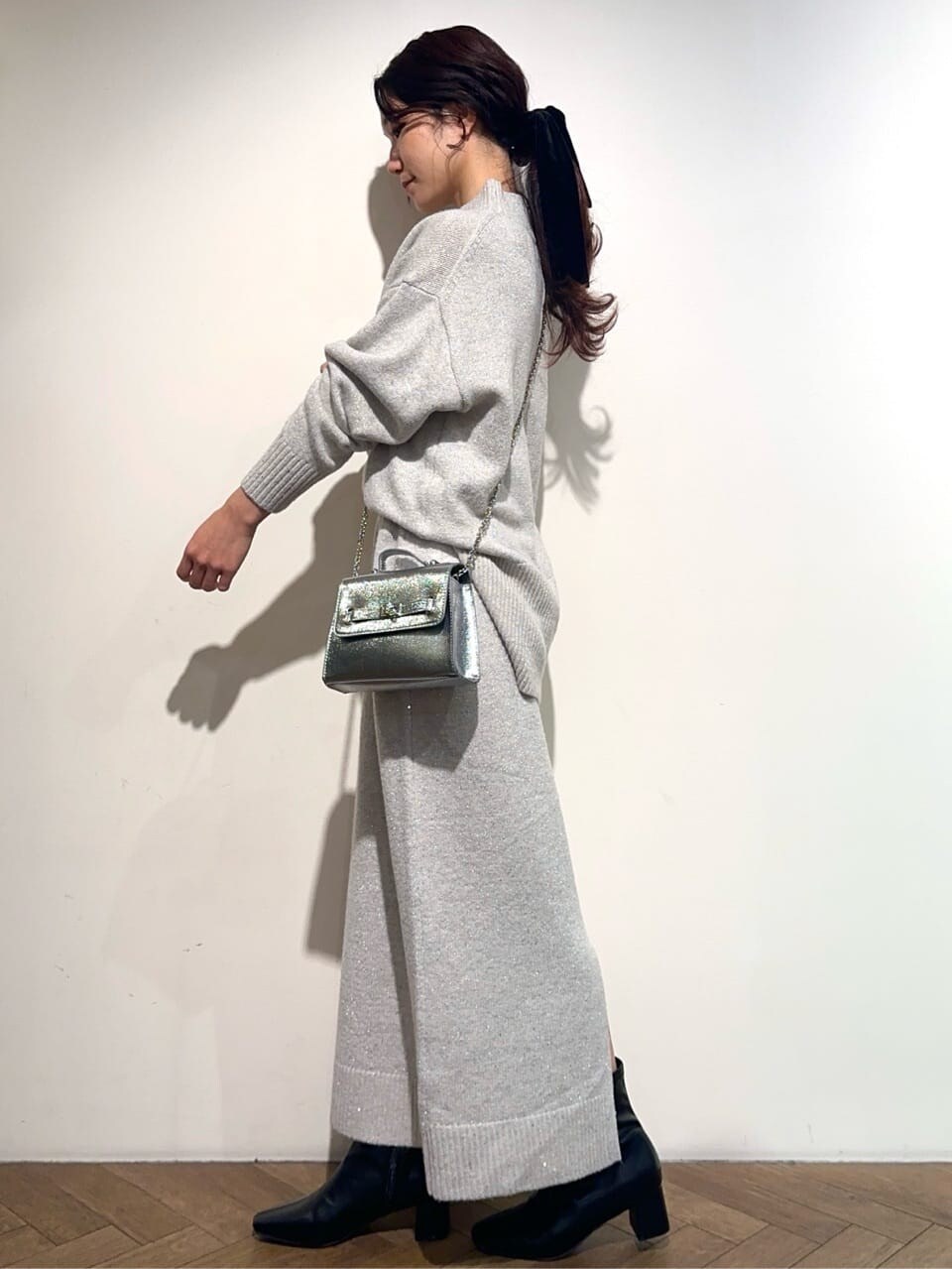 グレー系のニット/セーター、グレー系のスカート、シルバー系のショルダーバッグを着用したレディースの冬コーディネートの3枚目の写真