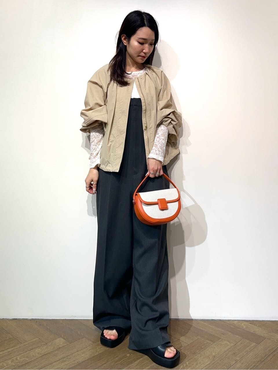 ベージュ系のノーカラーコート、ホワイト系のTシャツ/カットソー、グレー系のサロペット/オーバーオールを着用したレディースの春コーディネートの2枚目の写真