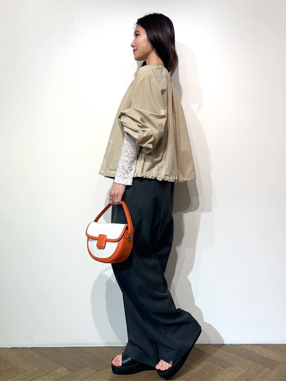 ベージュ系のノーカラーコート、ホワイト系のTシャツ/カットソー、グレー系のサロペット/オーバーオールを着用したレディースの春コーディネートの3枚目の写真