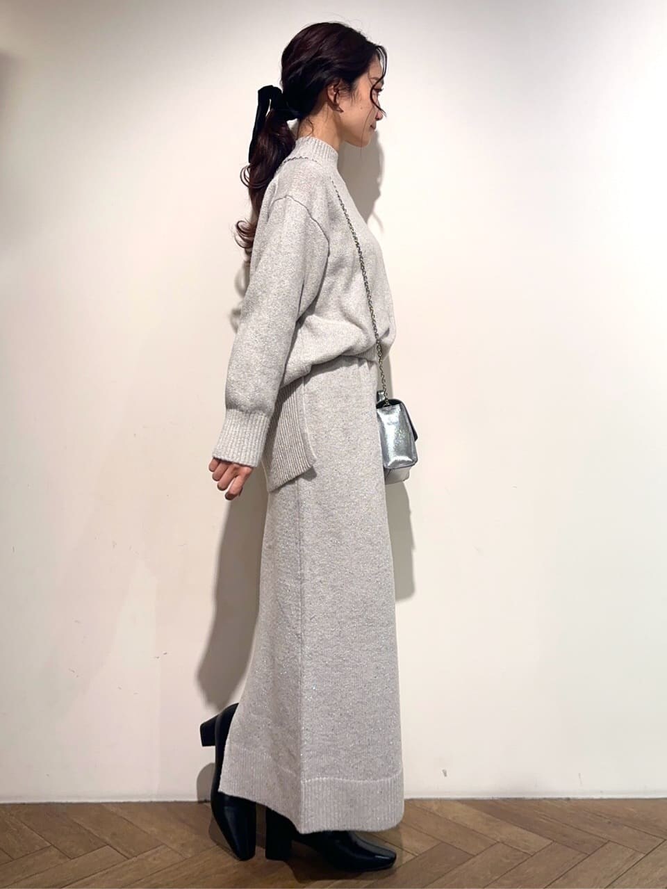 グレー系のニット/セーター、グレー系のスカート、シルバー系のショルダーバッグを着用したレディースの冬コーディネートの5枚目の写真