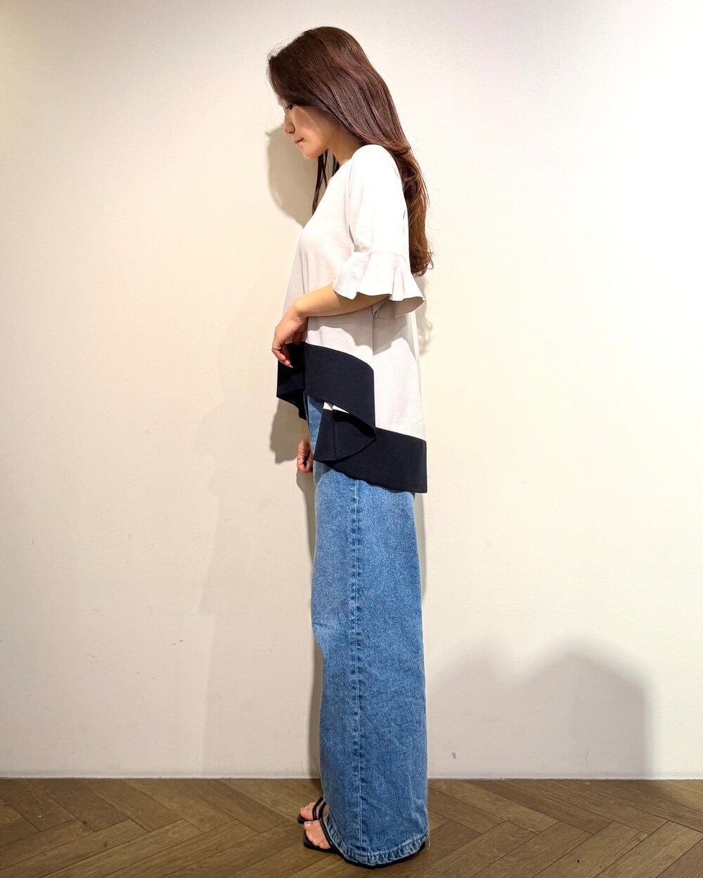 ベージュ系のニット/セーター、ブルー系のデニムパンツ、ブラウン系のハンドバッグを着用したレディースの春コーディネートの4枚目の写真