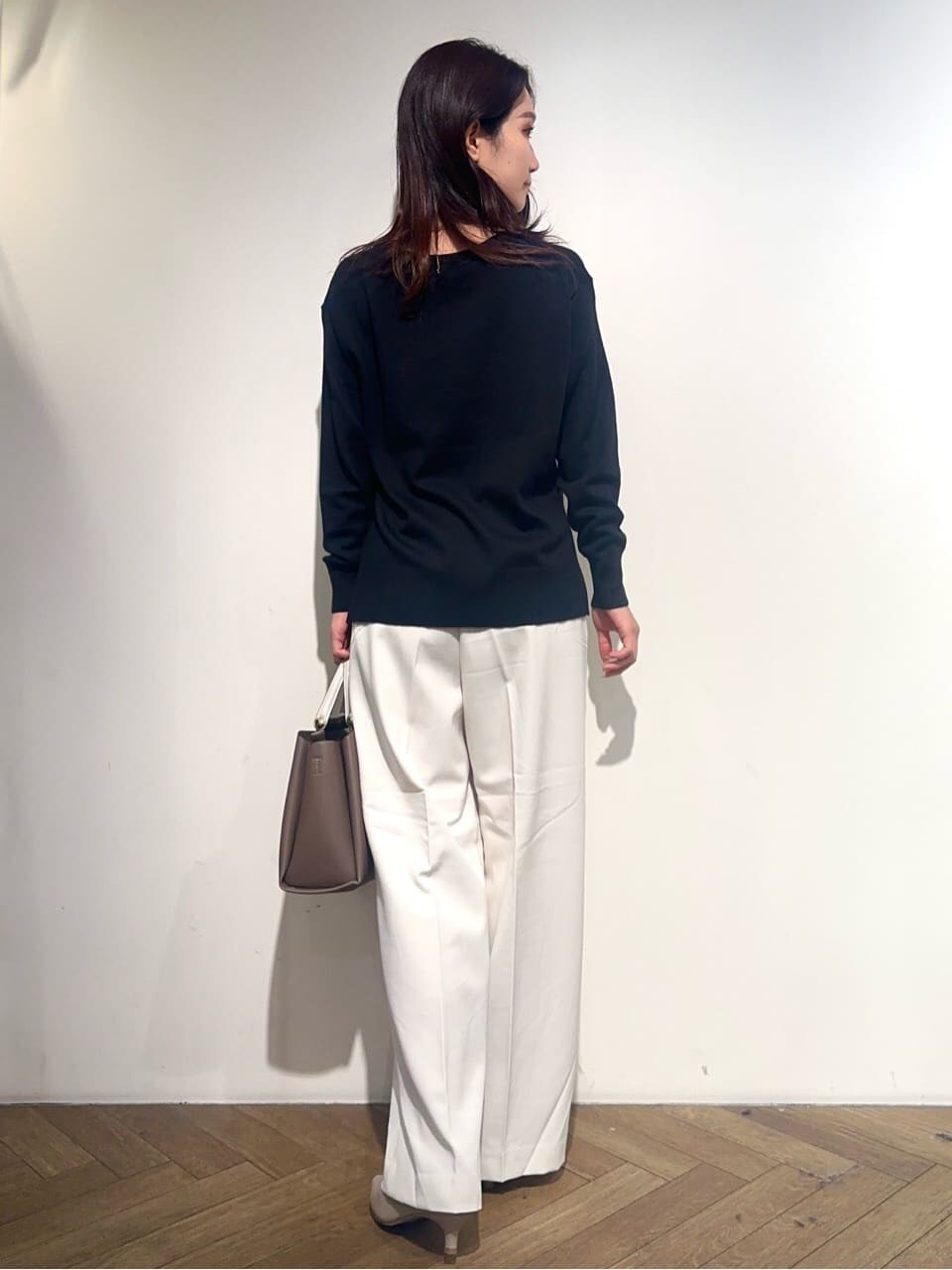 ブラック系のニット/セーター、ホワイト系のその他パンツ、ベージュ系のトートバッグを着用したレディースの秋コーディネートの3枚目の写真