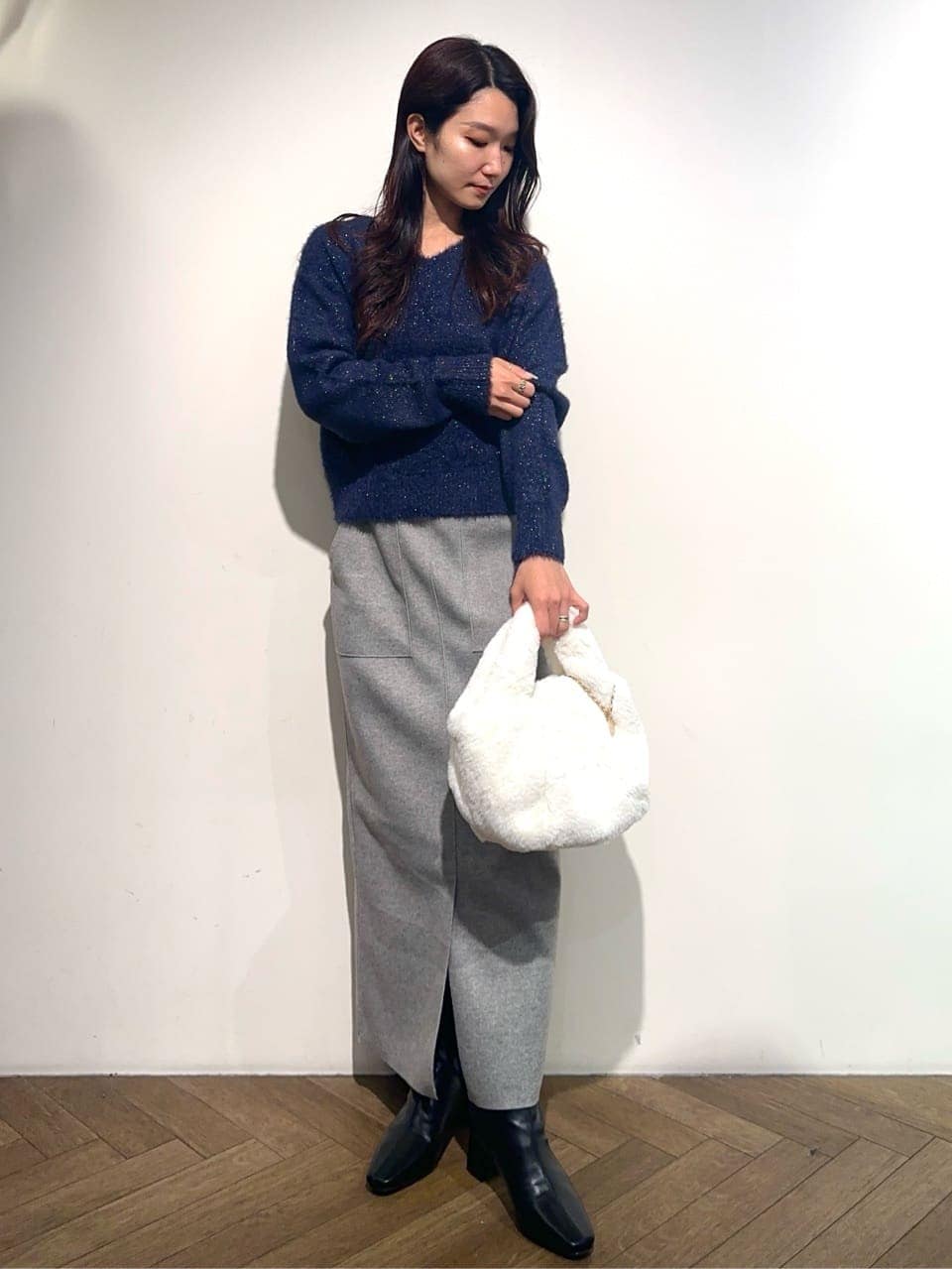 ブルー系のニット/セーター、グレー系のスカート、ホワイト系のトートバッグを着用したレディースの冬コーディネートの2枚目の写真