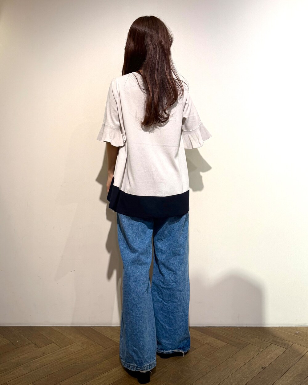 ベージュ系のニット/セーター、ブルー系のデニムパンツ、ブラウン系のハンドバッグを着用したレディースの春コーディネートの5枚目の写真