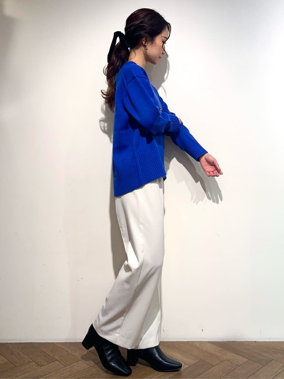 ブルー系のニット/セーター、ホワイト系のその他パンツ、ブラック系のブーツを着用したレディースの冬コーディネートの4枚目の写真