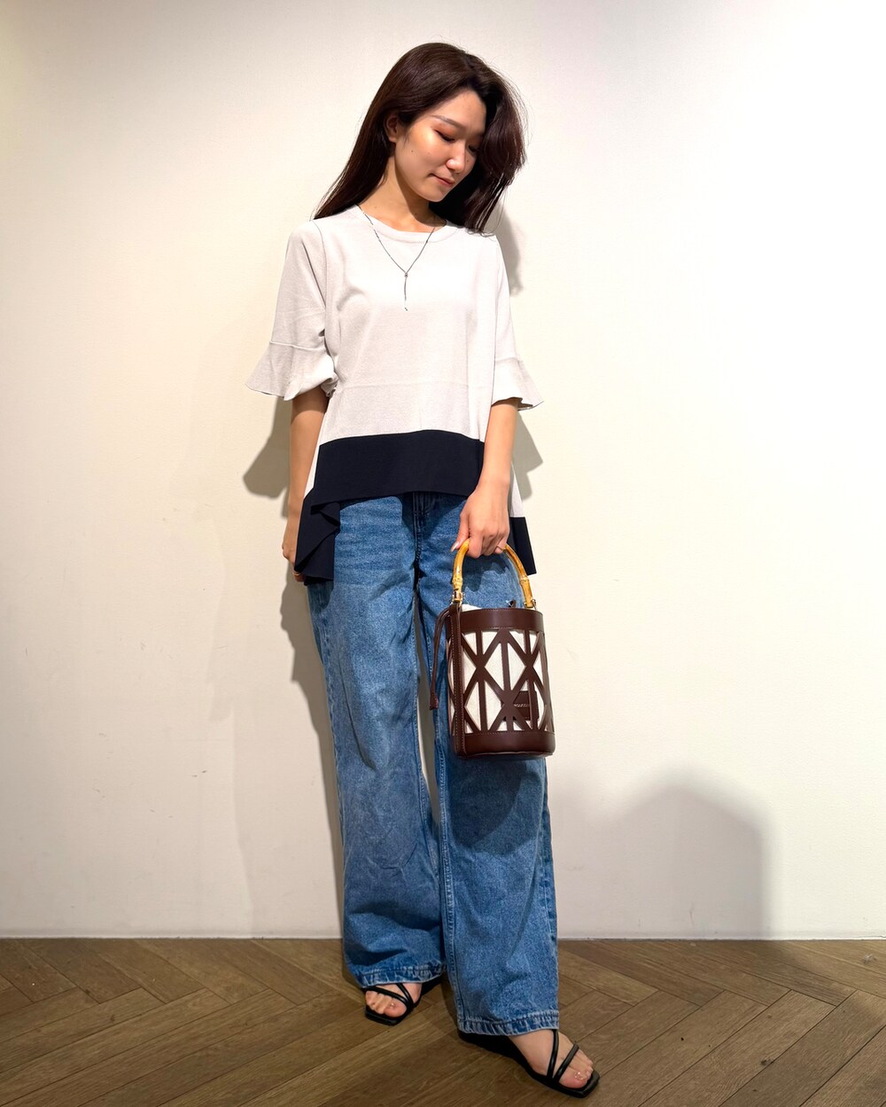ベージュ系のニット/セーター、ブルー系のデニムパンツ、ブラウン系のハンドバッグを着用したレディースの春コーディネートの3枚目の写真