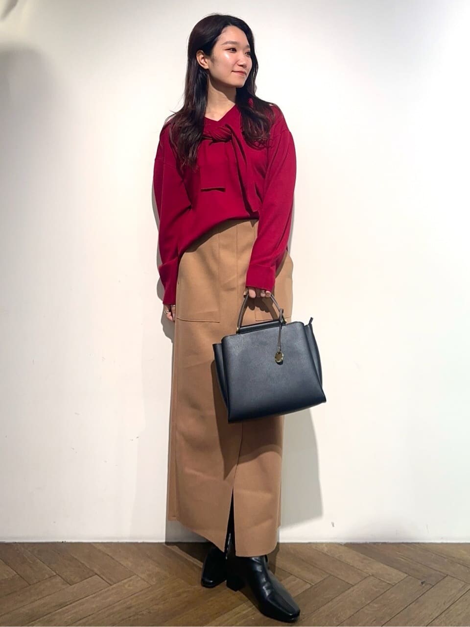 レッド系のニット/セーター、レッド系のカーディガン/ボレロ、イエロー系のスカートを着用したレディースの冬コーディネートの2枚目の写真