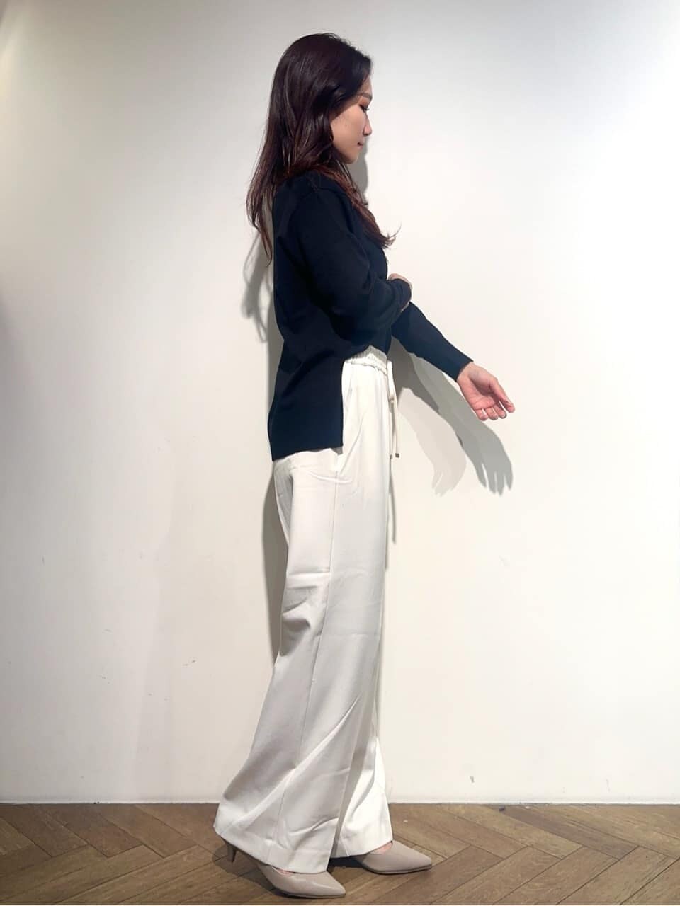 ブラック系のニット/セーター、ホワイト系のその他パンツ、ベージュ系のトートバッグを着用したレディースの秋コーディネートの4枚目の写真