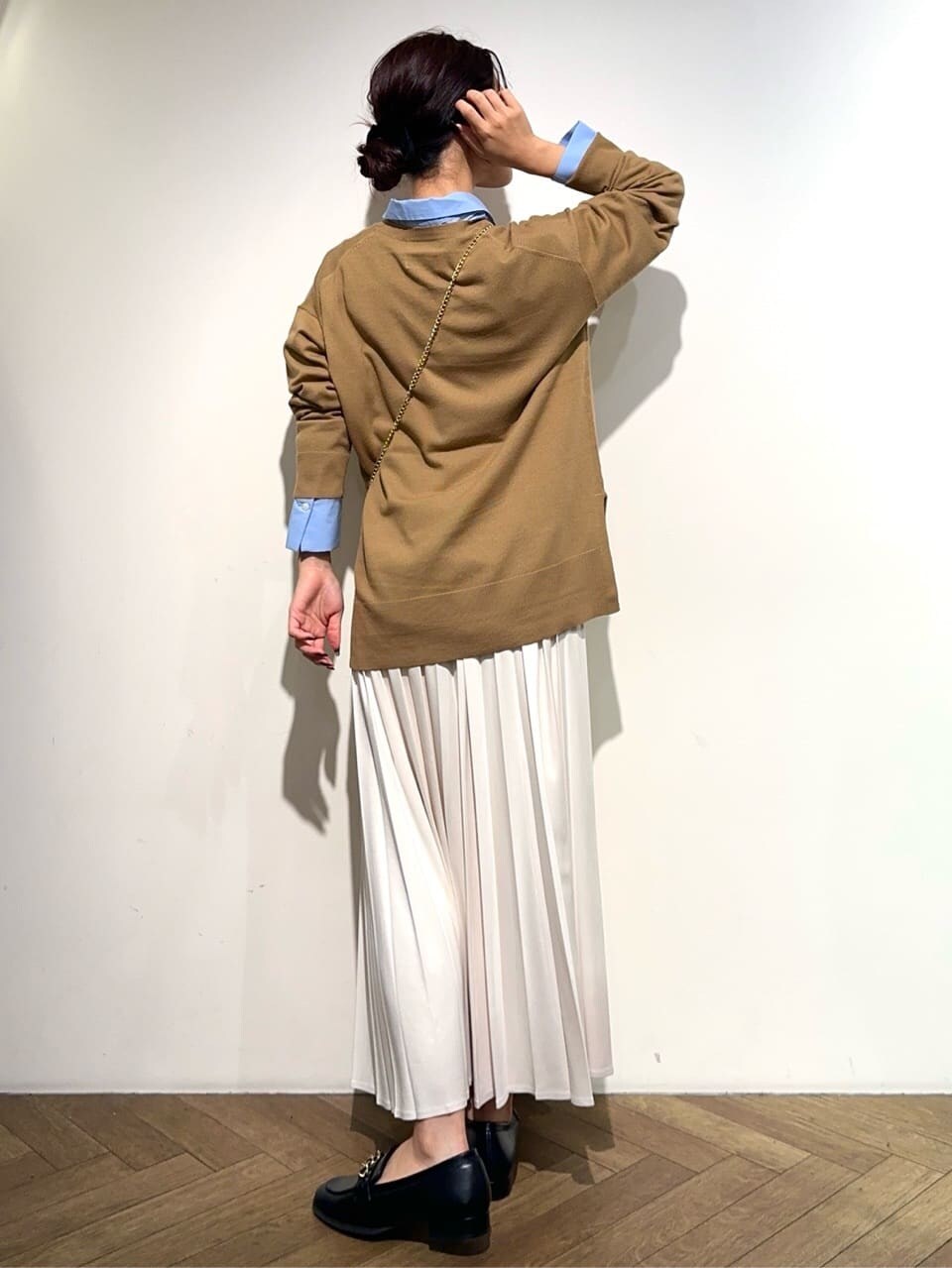 イエロー系のニット/セーター、ブルー系のシャツ/ブラウス、ホワイト系のスカートを着用したレディースの秋コーディネートの4枚目の写真