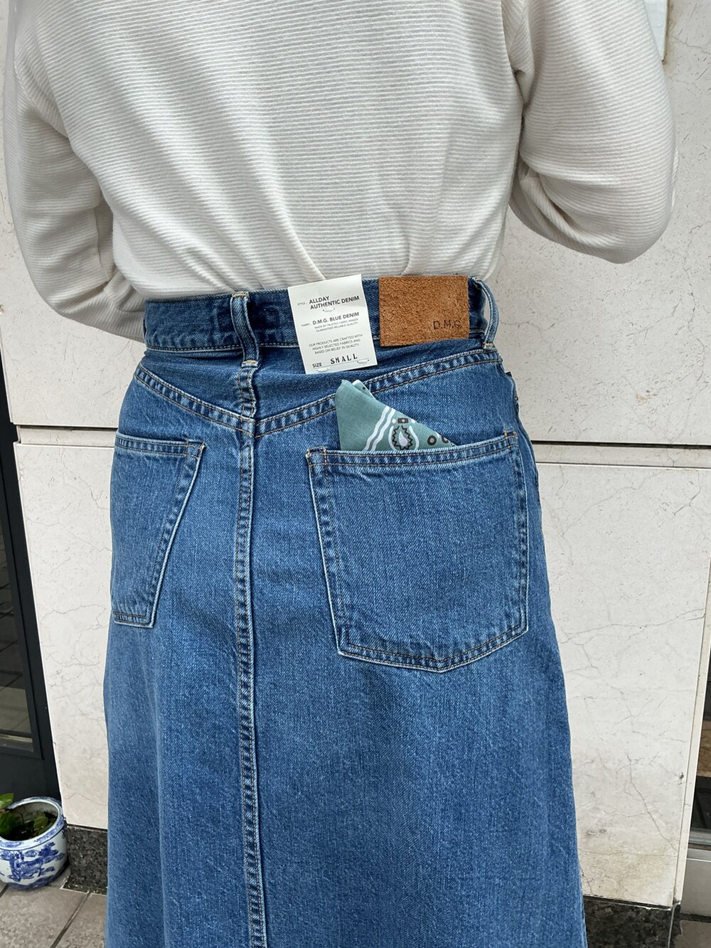 ホワイト系のTシャツ/カットソー、ブルー系のデニムスカート、ホワイト系のスリッポンを着用したレディースの夏コーディネートの3枚目の写真