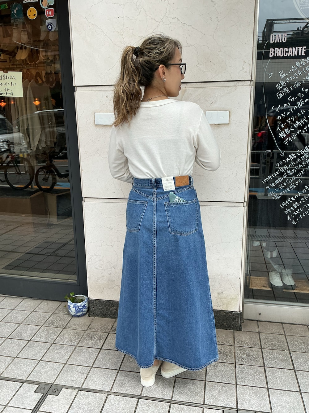 ホワイト系のTシャツ/カットソー、ブルー系のデニムスカート、ホワイト系のスリッポンを着用したレディースの夏コーディネートの2枚目の写真