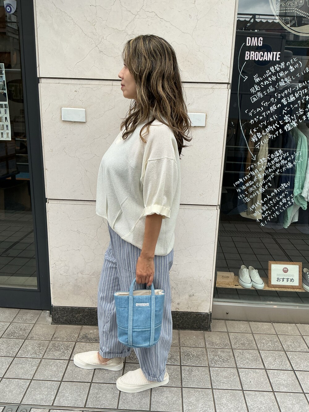 ホワイト系のニット/セーター、ブルー系のパンツ、ブルー系のバッグを着用したレディースの夏コーディネートの2枚目の写真