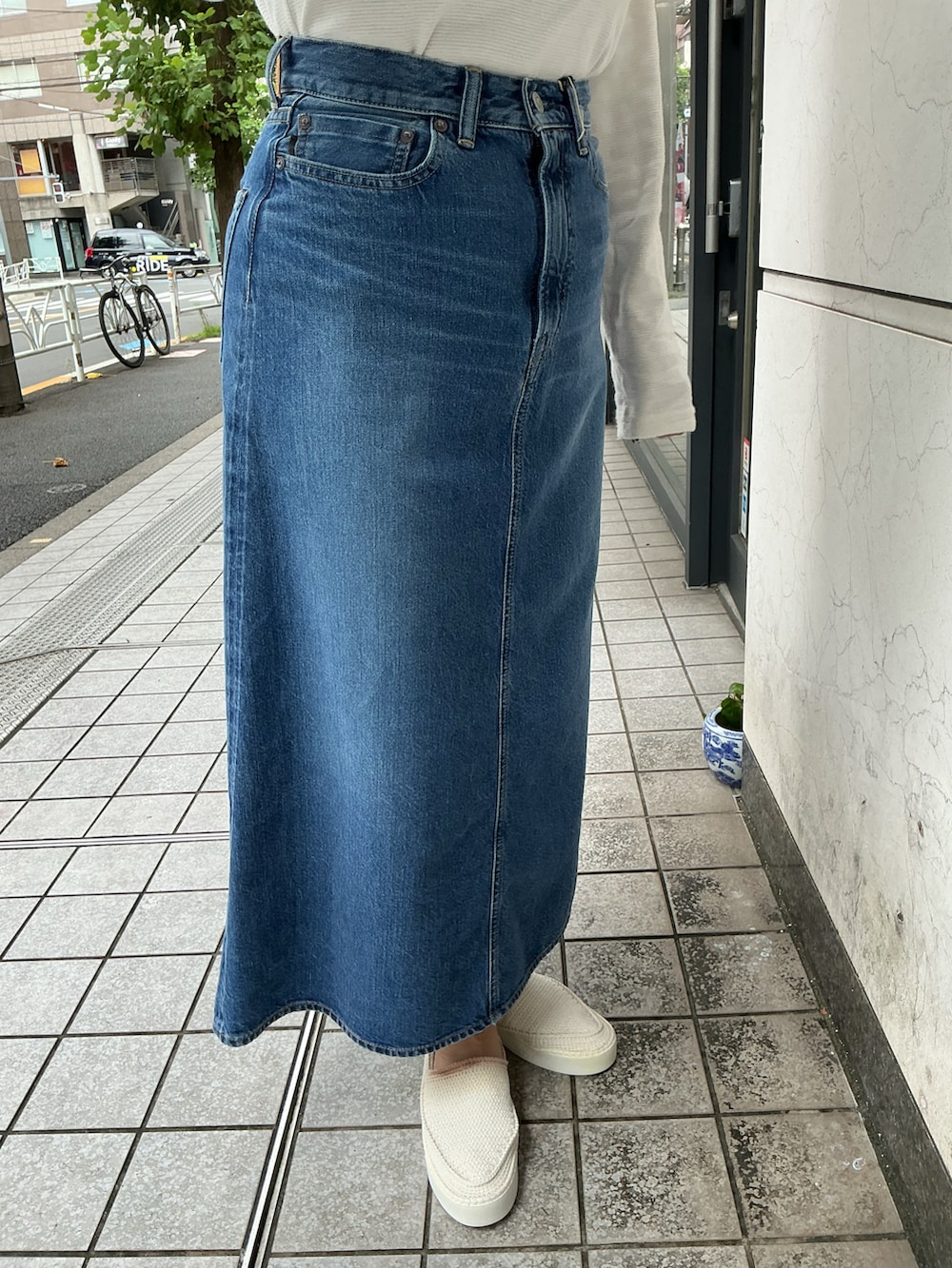 ホワイト系のTシャツ/カットソー、ブルー系のデニムスカート、ホワイト系のスリッポンを着用したレディースの夏コーディネートの4枚目の写真