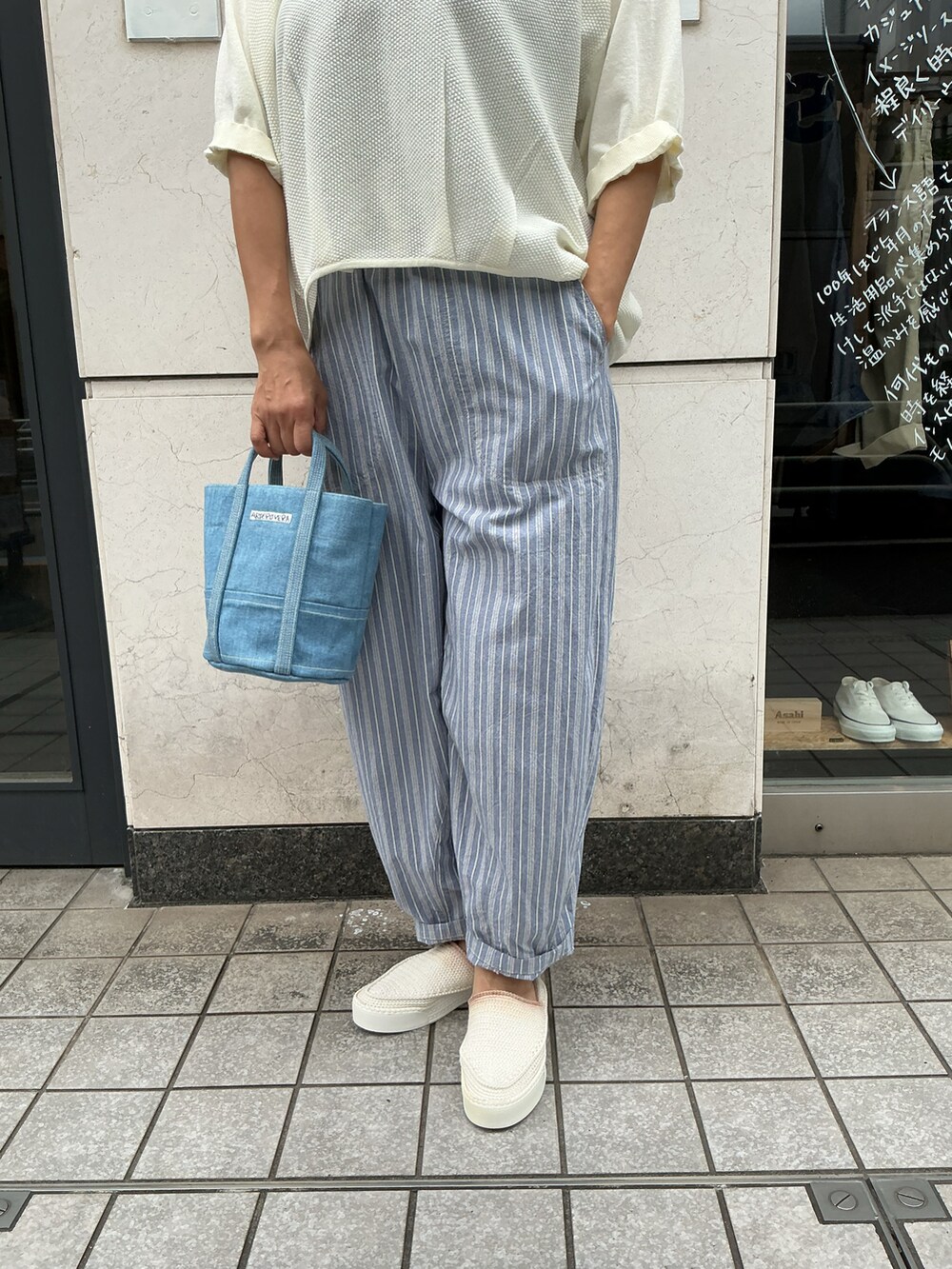 ホワイト系のニット/セーター、ブルー系のパンツ、ブルー系のバッグを着用したレディースの夏コーディネートの3枚目の写真