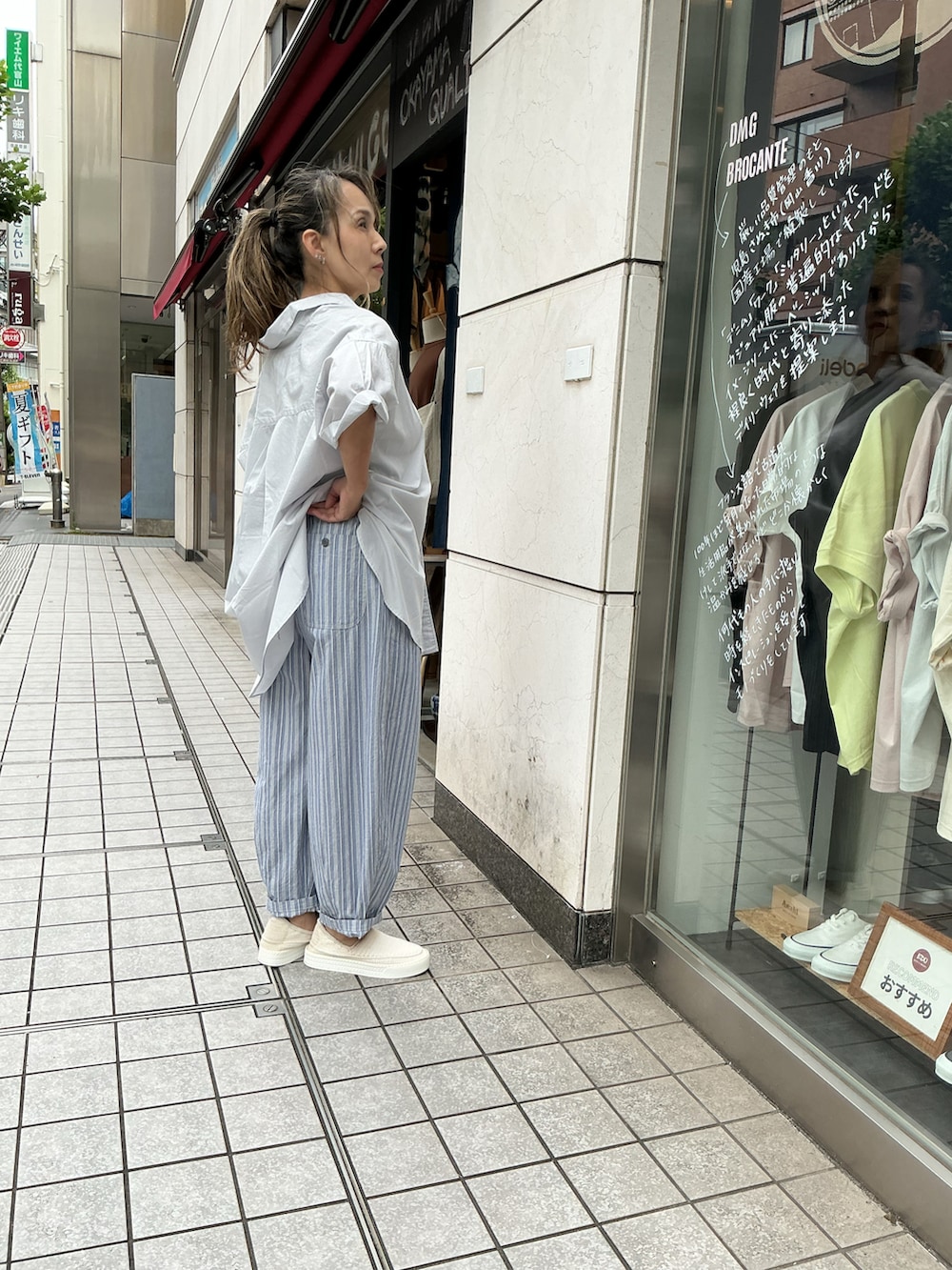 ホワイト系のシャツ/ブラウス、ブルー系のパンツ、ホワイト系のスリッポンを着用したレディースの夏コーディネートの2枚目の写真