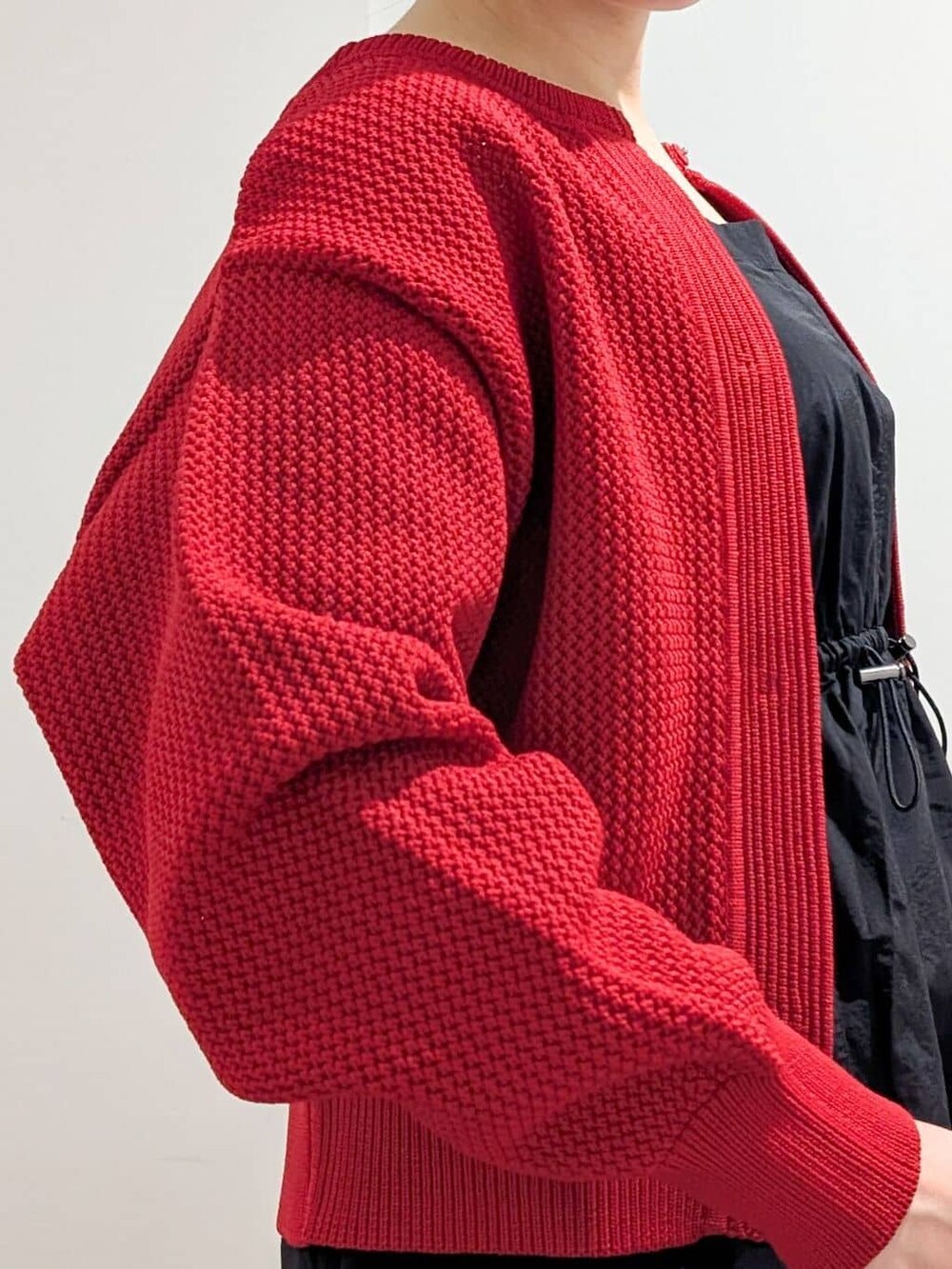ブラック系のワンピース、レッド系のカーディガン/ボレロ、ブラック系のサンダルを着用したレディースの春コーディネートの9枚目の写真