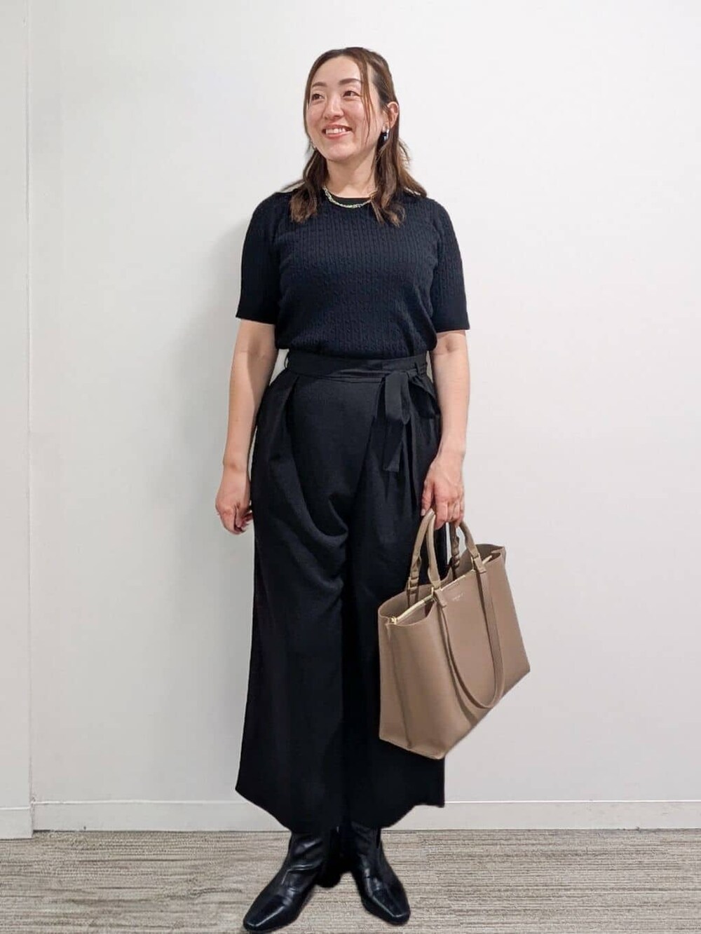 ブラック系のニット/セーター、ブラック系のその他パンツ、ベージュ系のトートバッグを着用したレディースの秋コーディネートの6枚目の写真