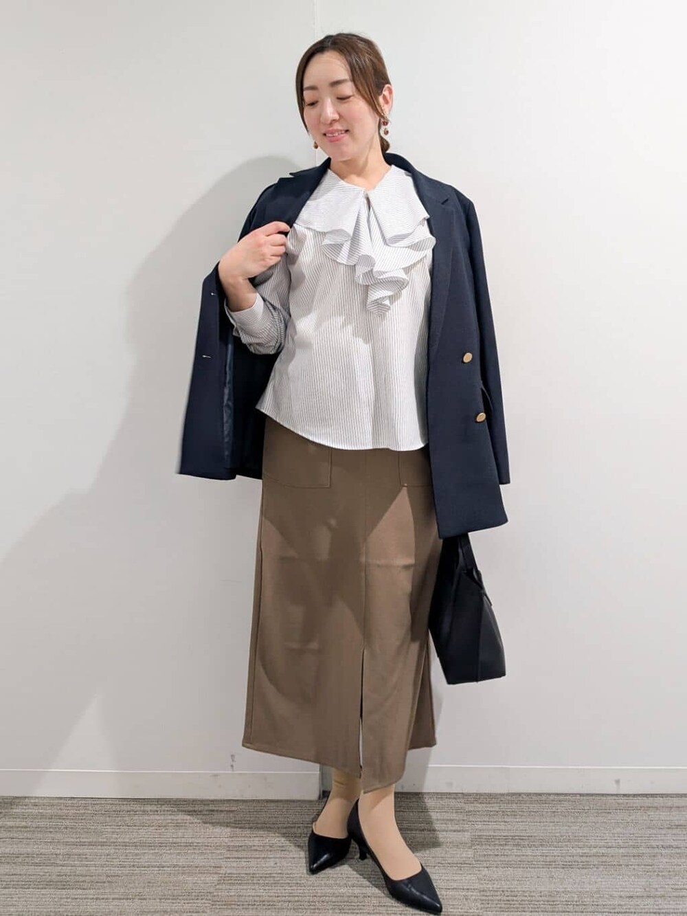 ブルー系のシャツ/ブラウス、ブラック系のパンプス、ブラウン系のスカートを着用したレディースの春コーディネートの3枚目の写真
