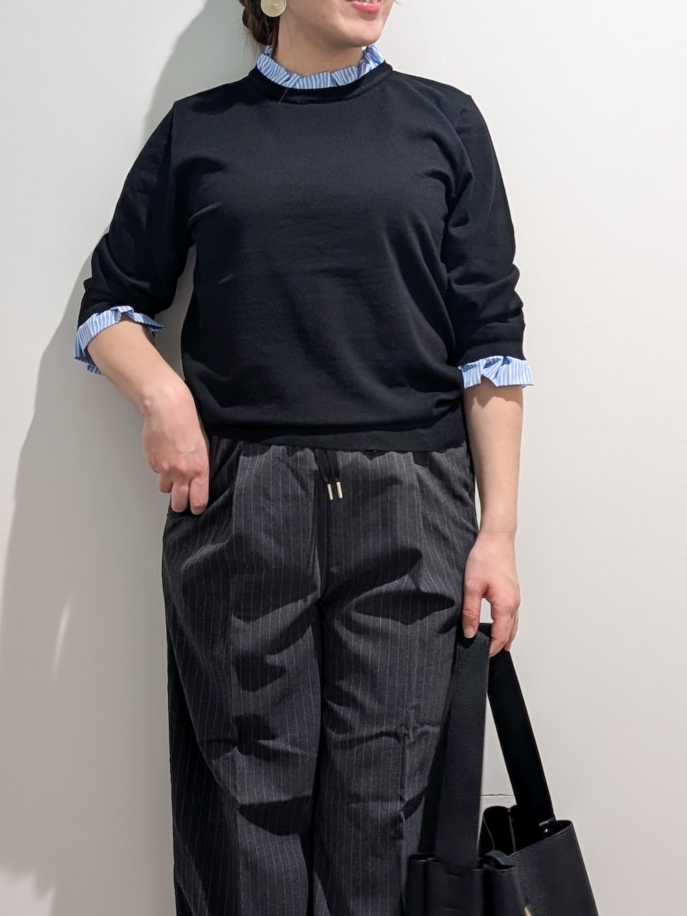 ブラック系のニット/セーター、グレー系のその他パンツ、ブラック系のトートバッグを着用したレディースの秋コーディネートの9枚目の写真